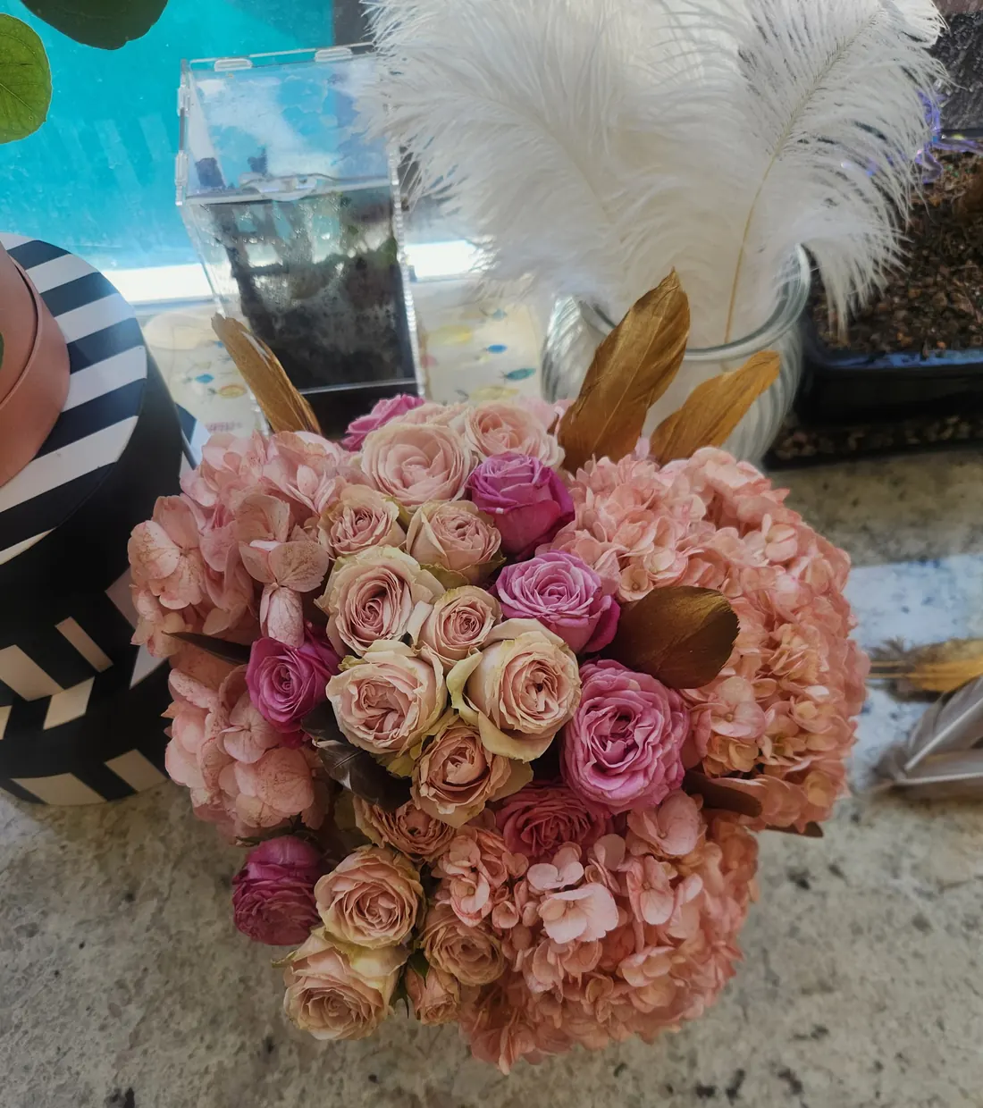 Round bouquet of pink hydrangeas and roses with gold feathers and white plumes